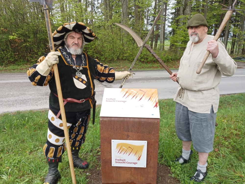 Jörg II. von Benzenau (l., Markus Schindele) und einer seiner aufsässigen Untertanen (r., Anton Reisach) an der Kemnater Gedenkstele für den Bauernkrieg.
Bildrechte: Stadtarchiv Kaufbeuren